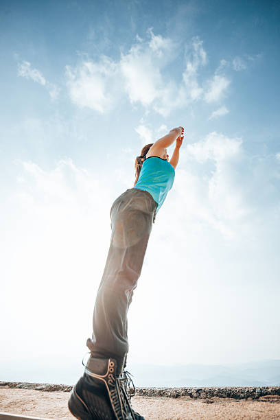 A woman in a hat and a blue T-shirt in a field, blue sky with clouds, rear view. Summer time. Village vacation. Time to travel