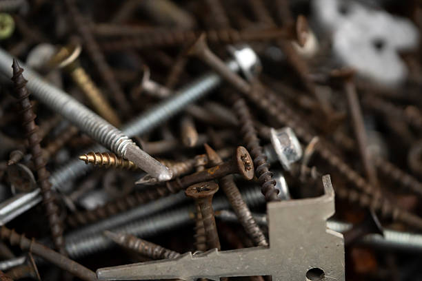 Screws and nails, tools for repair work, connection of structures, construction and handicraft closeup view on the dark background.