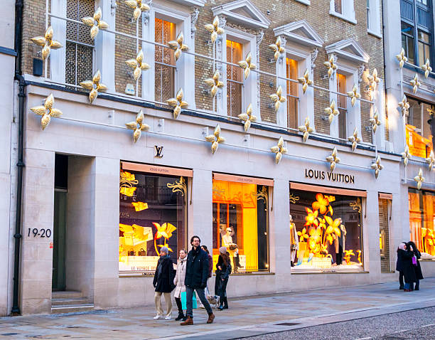 Pedestrians passing the flagship Louis Vuitton store in New Bond Street, Central London, which stocks luxury luggage items and leather goods. Christmas is coming!