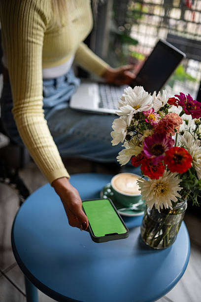 Woman working remotely holding smartphone with green screen