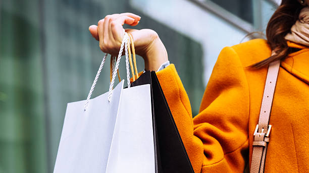 istock Shopping bags held by a person while walking outside in a city setting 2253407650