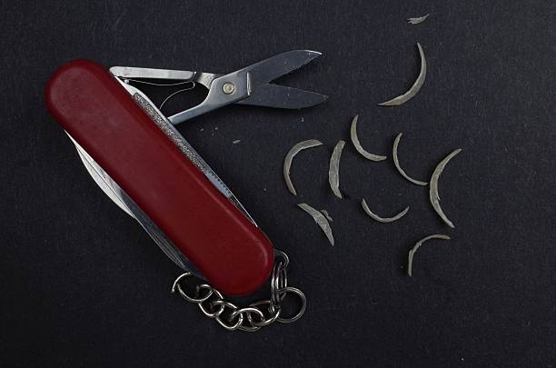 A red multi-tool knife with scissors, surrounded by small metal shavings on a dark background