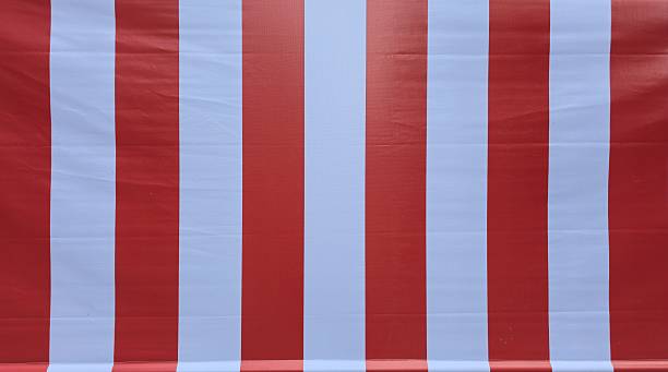 Close-up of vibrant red and white vertical striped canvas texture, ideal for abstract backgrounds in designs related to summer, beach, circus, or Christmas themes.