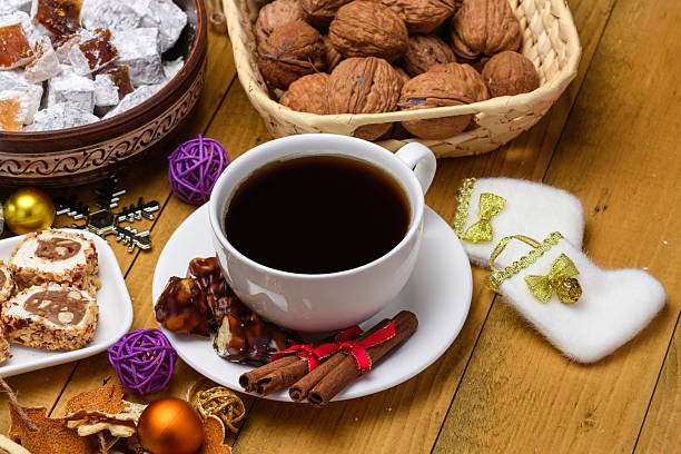 A cup of black coffee with Turkish sweets and walnuts on a festive Christmas table background.