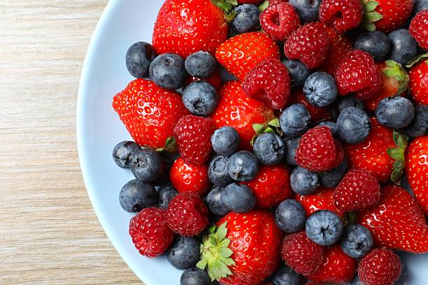 istock Different fresh ripe berries in bowl on the table, top view 2253415093