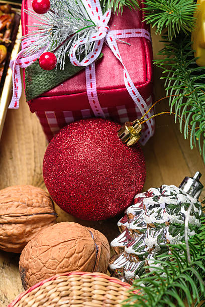 Christmas gift box with red ball and walnuts on wooden background