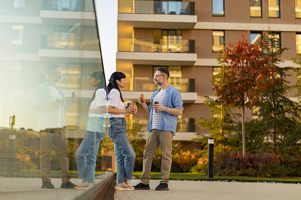 istock Two colleagues on the break engaging in conversation outdoor while holding coffee cups and their meals. 2253421479