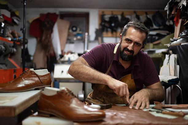 Leather shoemaker at work in a cluttered workshop crafting polished brown shoes