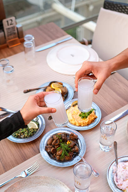 A group of friends sharing traditional Turkish meze dishes at a restaurant table. Close-up view of hands serving and tasting appetizers such as salads and cold starters, creating a warm and social dining atmosphere. Concept of friendship, Mediterranean cuisine, and social eating.