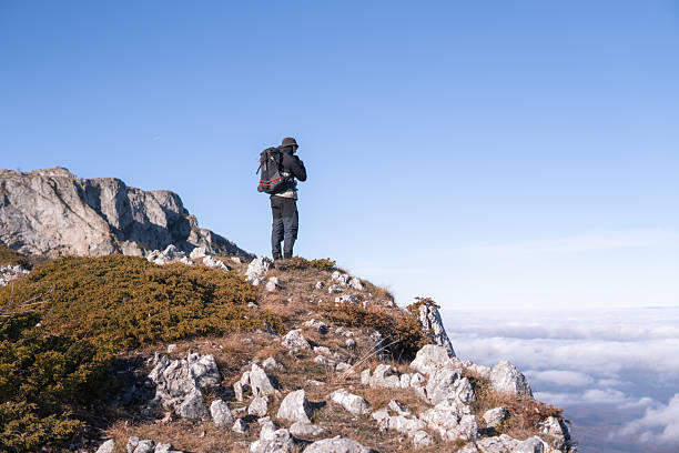 istock Man standing on the mountain cliff above the clouds 2253427919