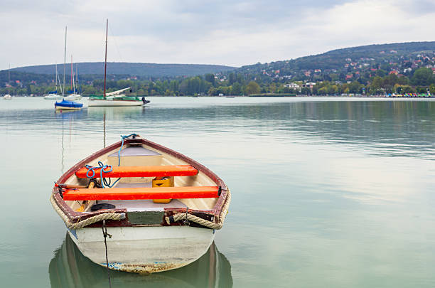 Boat with a blue tarp on top sits in the water. The boat is small and has a white top