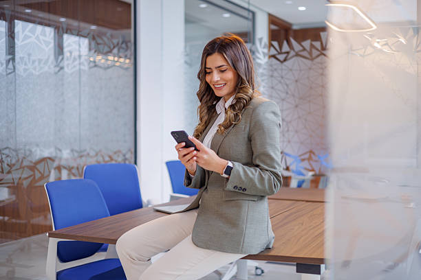 istock Young businesswoman sending text message using smartphone, connecting with colleagues in modern office environment 2253430981