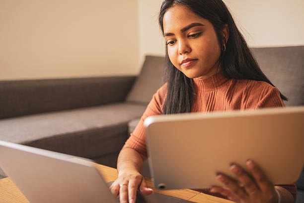 istock Woman multitasking at home with laptop and tablet for efficient work 2253431400