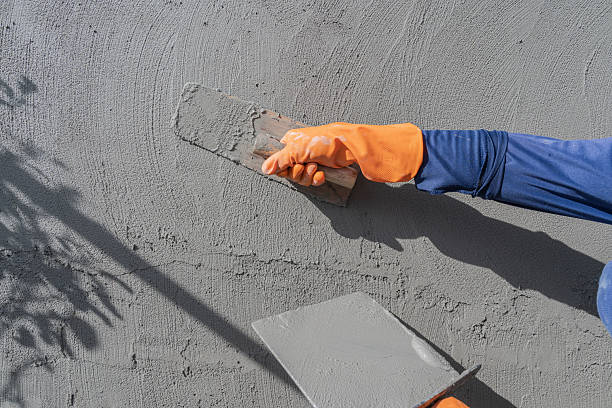 istock Hand worker plastering with holding trowel handle wet grey cement mix Plaster wall concrete Backgrounds 2253433521