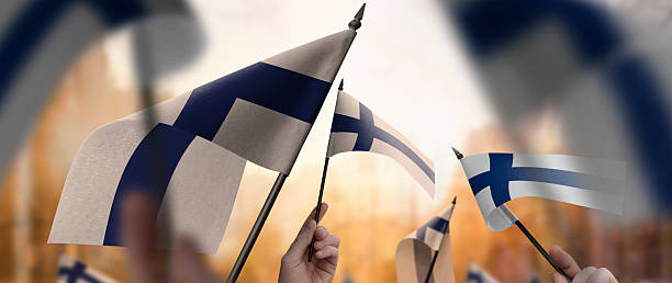 istock Finland flags in their hands on a blurred urban background 2253441344