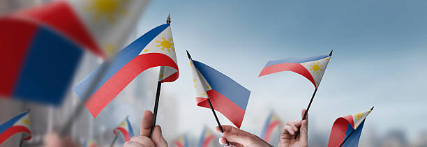 istock Philippines flags in their hands on a blurred urban background 2253441349