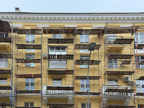 istock Workers are putting up scaffolding on a yellow building with multiple balconies 2253441639