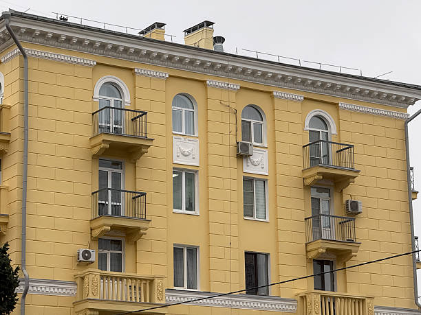 Building features multiple balconies and air conditioning units in a city setting.