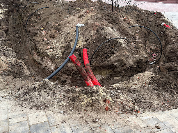 istock Workers are digging a trench in the ground while exposing cables and dirt in the city 2253441689