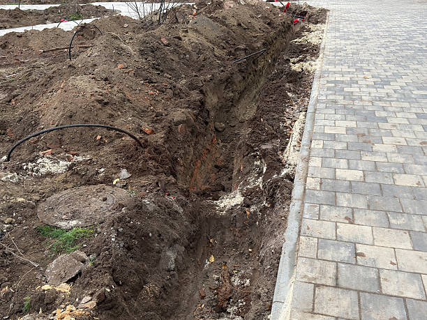 istock Workers dig a trench beside the sidewalk for construction near a bare area 2253441694