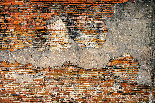 A striking close-up of a textured brick wall featuring peeling plaster and weathered elements. The interplay of colors and patterns evokes a sense of history.