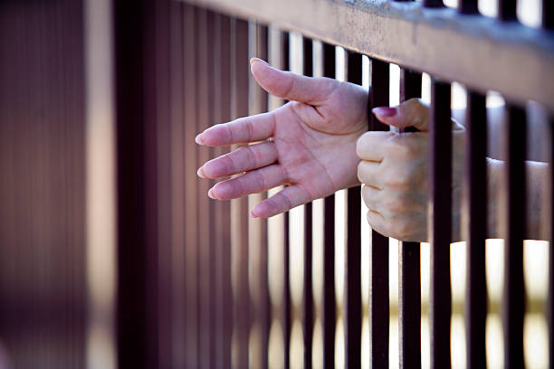 istock Hands Reaching Through Iron Bars of a Jail or Prison Cell 2253442266