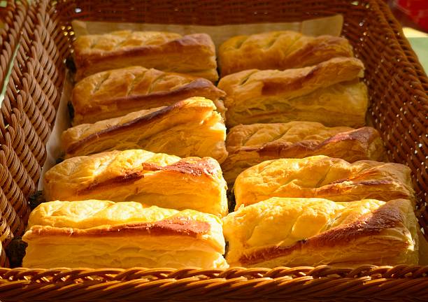 Freshly baked puff pastries arranged in wicker baskets at a bakery display. Golden, flaky layers and warm lighting create an inviting atmosphere, highlighting freshness and quality. Suitable for bakery business, food marketing, breakfast concepts, café promotion, artisan baking, and commercial food-related content.