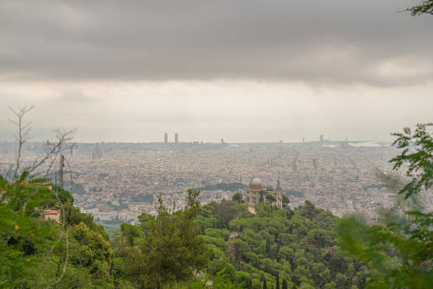 A city view with a cloudy sky and a few trees in the background. The city is full of buildings and the sky is overcast