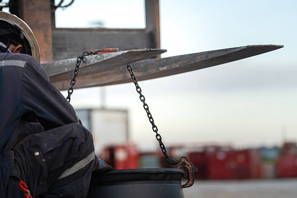 Asian blue collar coworkers rigging up chains to a pulley system for heavy lifting