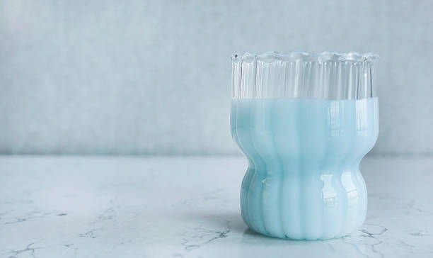 Pastel Blue Milk or Smoothie in Ribbed Glass on White Marble Table, studio shot with copy space