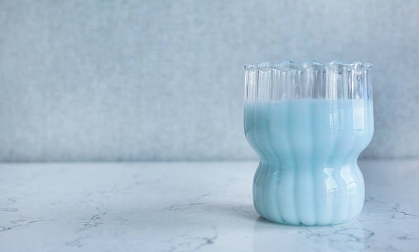 Pastel Blue Milk or Smoothie in Ribbed Glass on White Marble Table, studio shot with copy space