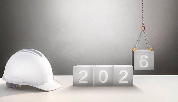 istock Happy New Year 2026 Construction and Industry. White Helmet and a numbered concrete cube on the desk of an engineer or construction worker. building with Cranes construction concept. 2253448093