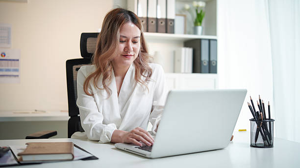istock Confident young businesswoman using a laptop in a bright office space. 2253448361