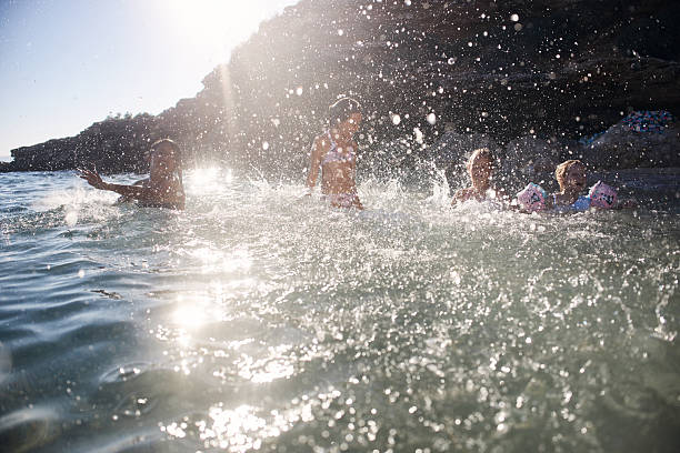 Kids splashing and playing with water in a sunny ocean