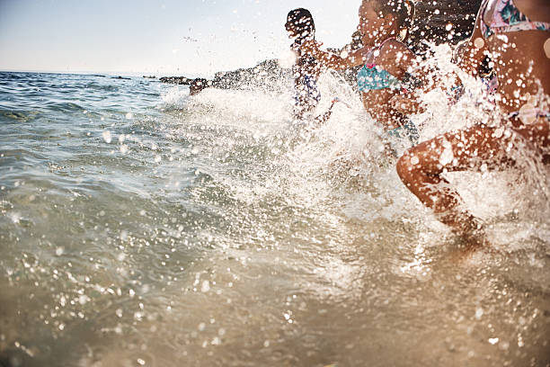 Kids running in shallow sea waves, creating water droplets and enjoying holidays