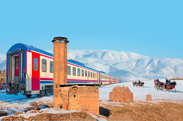 istock Red diesel train (East express) in motion at the snow covered railway - Horses pulling sleigh in winter - Ani Ruins, Ani is a ruined and  medieval Armenian city - Kars, Turkey 2253449553