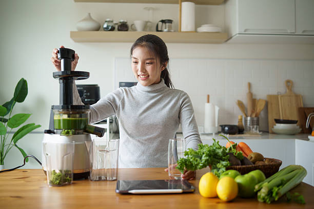 istock Smiling young woman preparing a nutritious green drink in a bright modern kitchen. Healthy lifestyle concept 2253449616