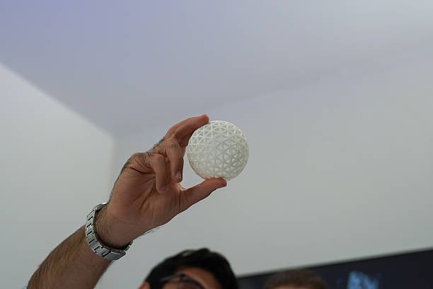The focus is on the researchers' hands as they work with a 3D printer to print a clear white plastic model, using cutting-edge, spot-on technology in the lab.