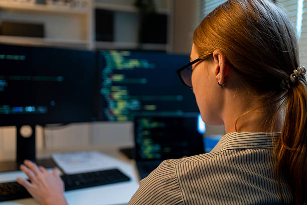 istock Close up of young female software engineer working at night in office. Programmer IT technician looking at computer, creating solutions and develop technology security in workplace during evening. 2253450887