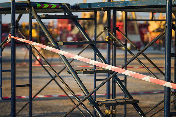 Red and white stripe barricade tape using to control danger zone in construction working site. Close-up and selective focus in foreground.