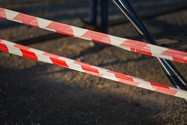 Red and white stripe barricade tape using to control danger zone in construction working site. Close-up and selective focus in foreground.