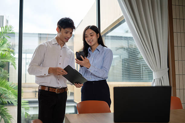 istock Male and female colleagues smiling while collaborating with digital devices in a modern workplace. 2253451747