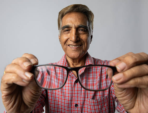istock Old man checking his eyeglasses on white background 2253452042