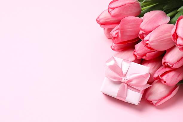 istock Beautiful fresh pink tulips with gift box on color background 2253456719