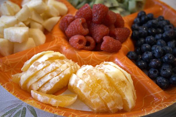 Mixed cut fruits on orange serving plate close-up