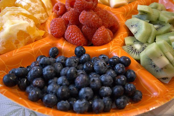 Mixed cut fruits on orange serving plate close-up