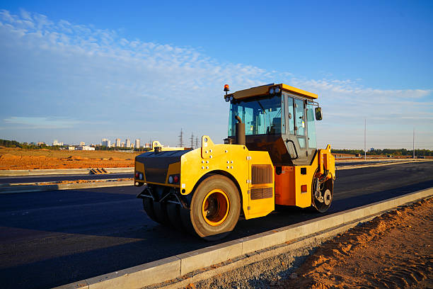 istock Heavy Machinery Compacts Asphalt on Construction Site. Road roller working on newly laid asphalt surface on sunset blue sky. 2253460203