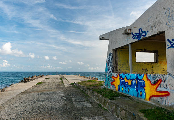Black Sea shore. Woman at the pier and water and monitoring point with graffiti. Pomorie town, Bulgaria, Eastern Europe.
