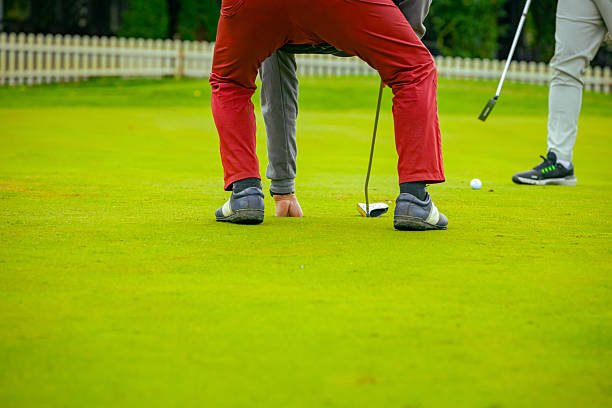 Asian man and his elderly father enjoy a morning round of golf together under the warm sunlight, surrounded by nature on a wild golf course. Mental health, exercise and care in senior people.