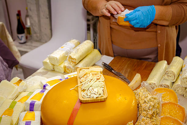 Woman is selling various type of homemade cheese at indoor stall, stand, private event.